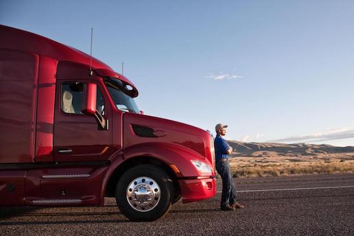 Small business truck driver standing with a truck.