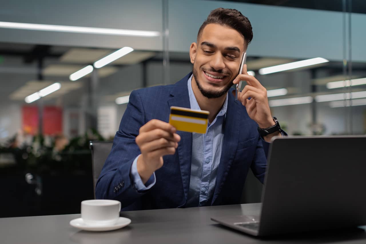 Small business owner examining a credit card while talking on the phone.