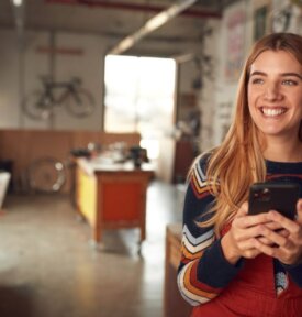 Small business owner holding phone and smiling.